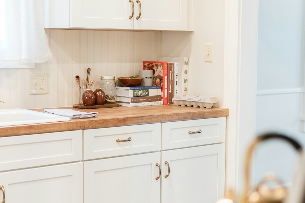 Bright kitchen with white cabinetry and natural wood countertops